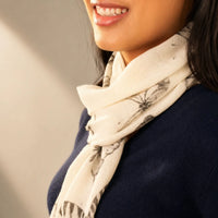 Cashmere-Schal in Creme mit grauem Pflanzenmuster, leicht gerollt am Hals