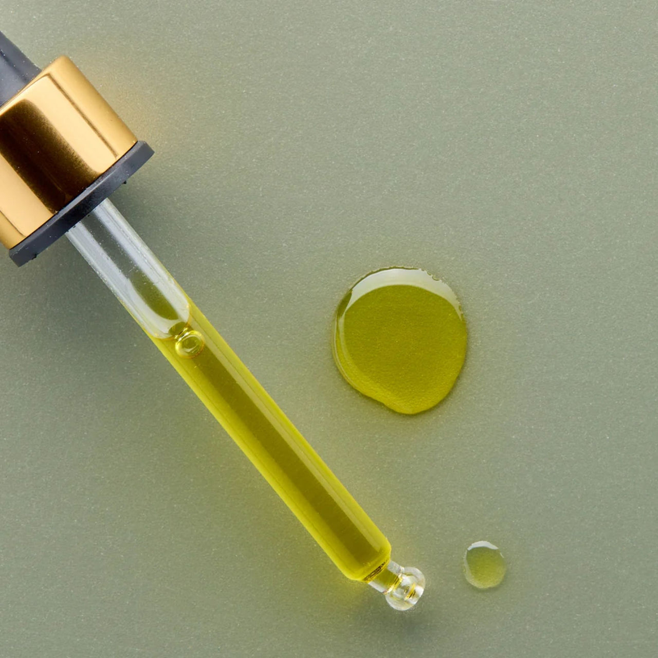Gesichtsöl im Tropferfläschchen mit goldener Flüssigkeit und kleiner Ölkuppel